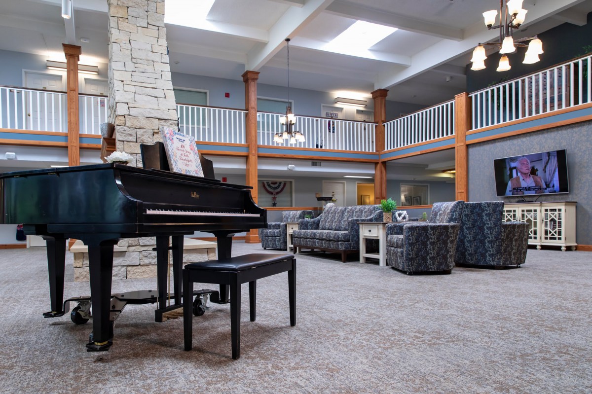 A spacious lounge area featuring a grand piano, comfortable seating, and ample natural light through skylights.