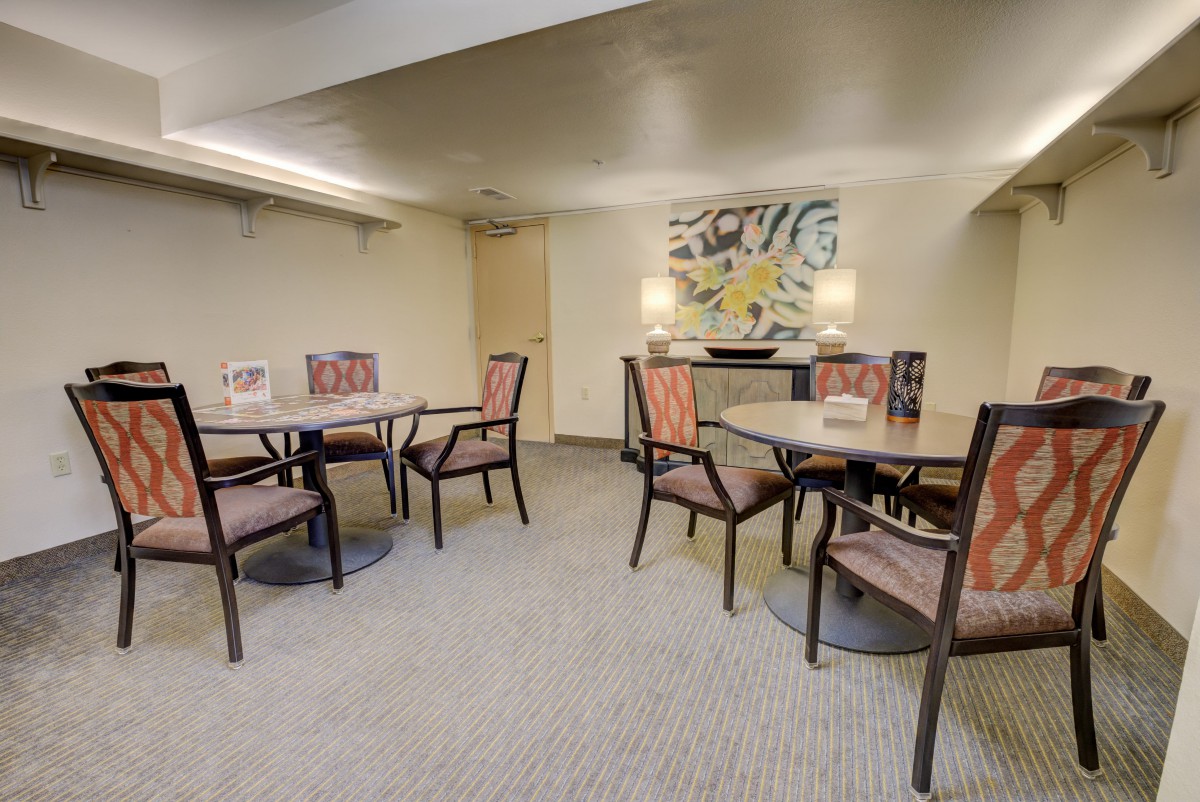 A cozy dining area with tables and chairs, adorned with artwork and carpet flooring.