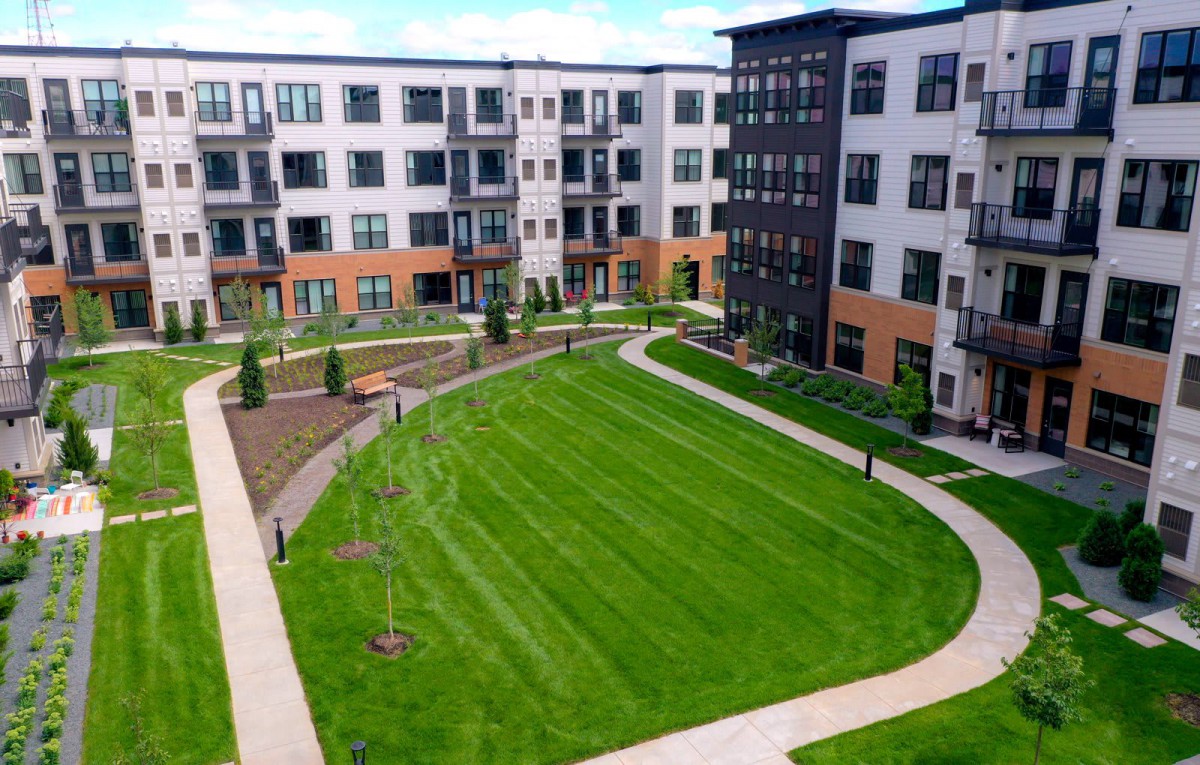 A modern apartment complex with a spacious green lawn in the courtyard.