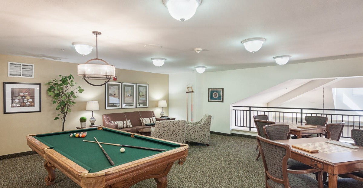 A cozy game room featuring a billiard table, seating area, and modern lighting.