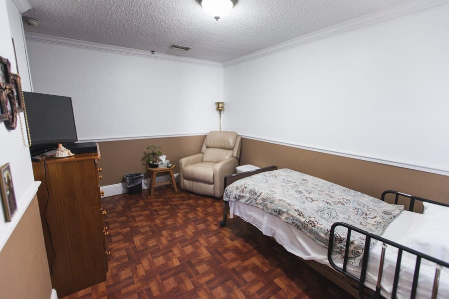 A simple room featuring a single bed, an armchair, and basic furnishings.