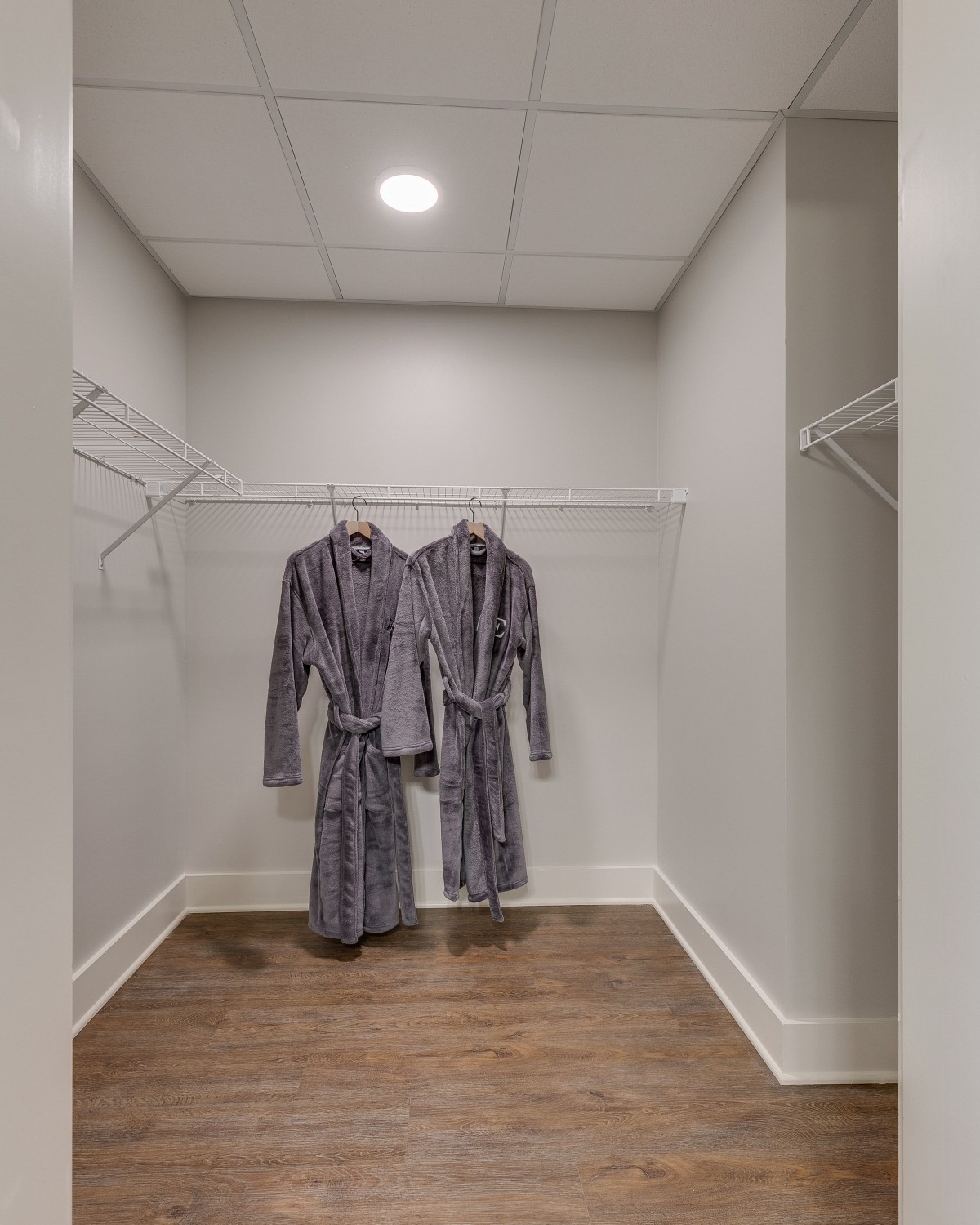 A walk-in closet with two robes hanging on a rack.