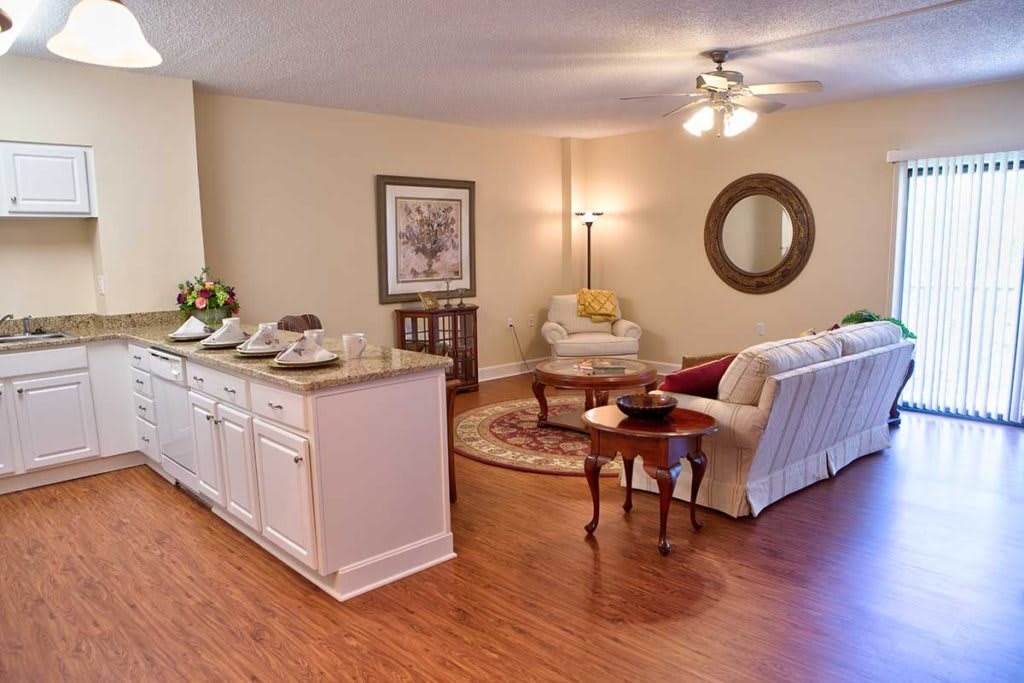 A cozy living room with a sofa, armchair, and wood flooring.