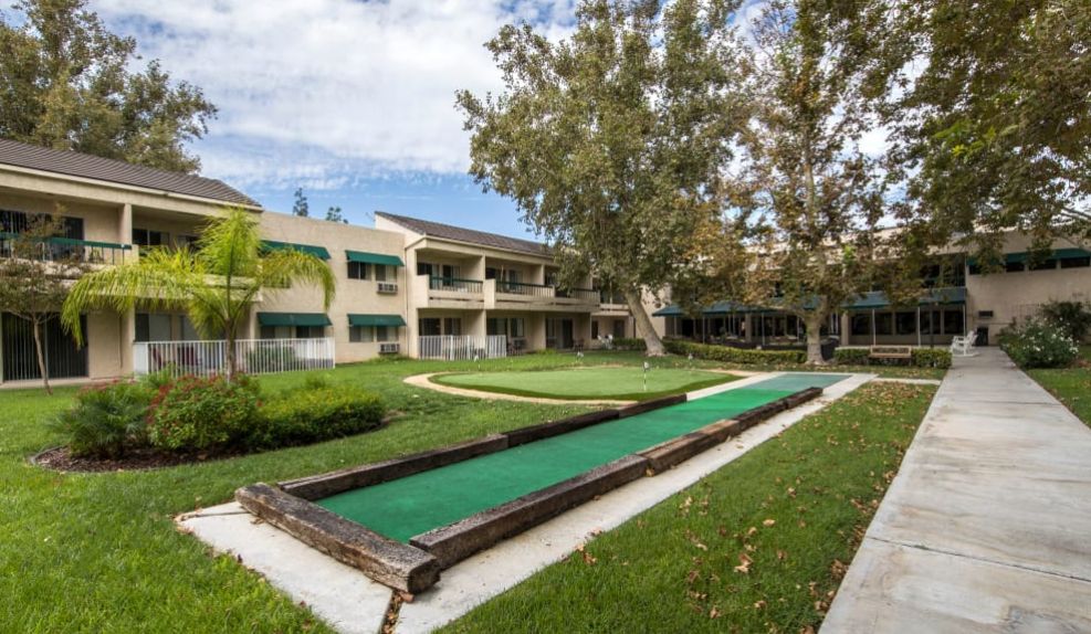 A residential building with a bocce court and landscaped outdoor area.