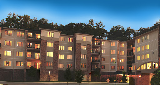 A modern apartment building illuminated at dusk, showcasing its architectural features and inviting atmosphere.