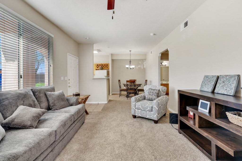 A cozy living room with a sofa, armchair, and dining area in view.