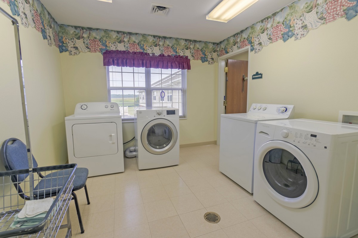 A well-lit laundry room with multiple washing machines and a dryer.