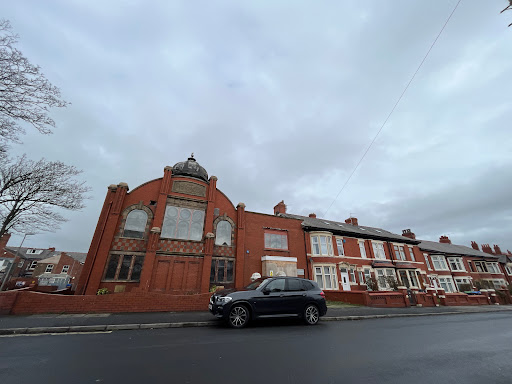 A view of a distinctive building adjacent to residential homes on a cloudy day.