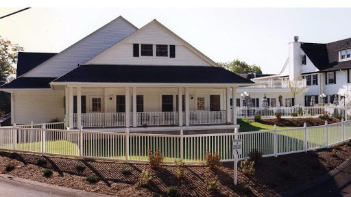 A charming white house featuring a spacious front porch and well-maintained landscaping.