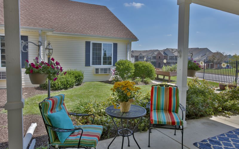 A cozy patio setup with colorful chairs and a table overlooking a well-maintained garden.