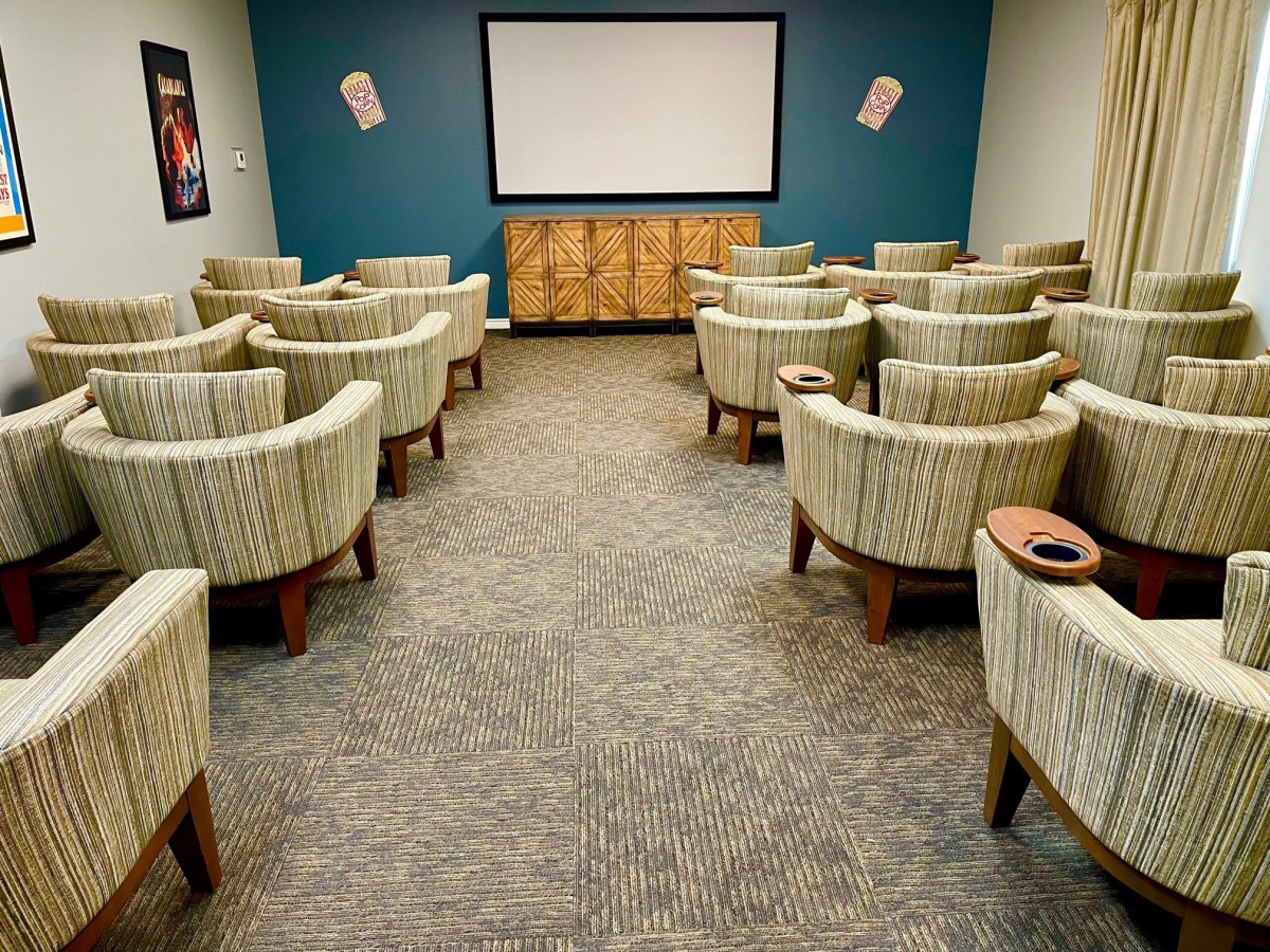 A cozy home theater with multiple rows of comfortable chairs facing a large screen.