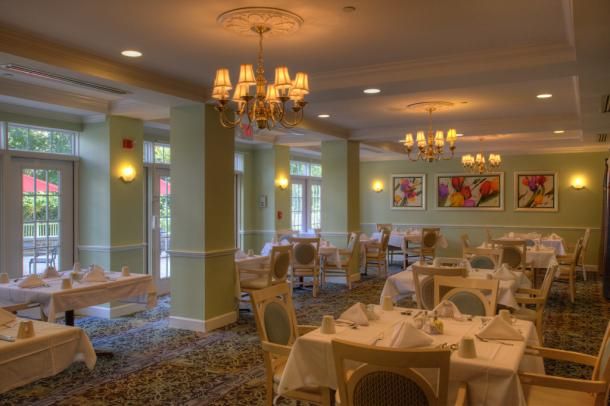 An elegant restaurant dining room with neatly set tables and classic chandeliers.