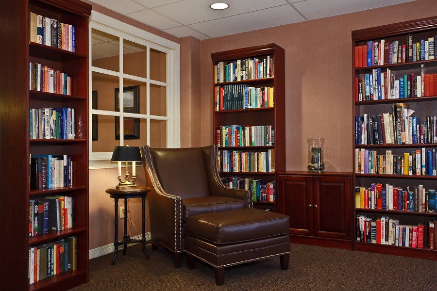 Cozy reading nook with a leather armchair surrounded by bookshelves.