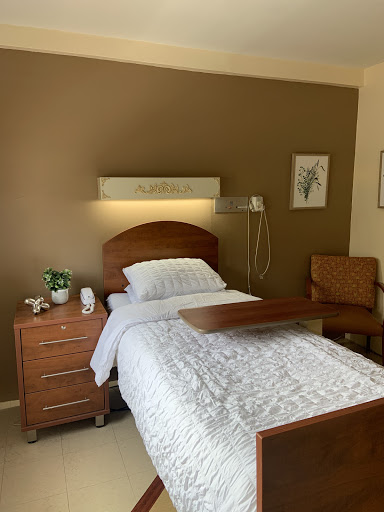 A serene hospital room featuring a neatly made bed alongside essential furniture.