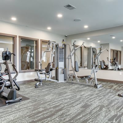 A well-equipped fitness center with various exercise machines and mirrors lining the walls.