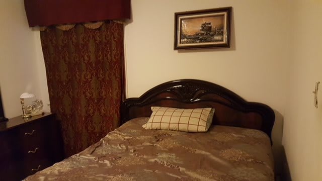 A cozy bedroom with a neatly made bed, decorated pillow, and artwork on the wall.