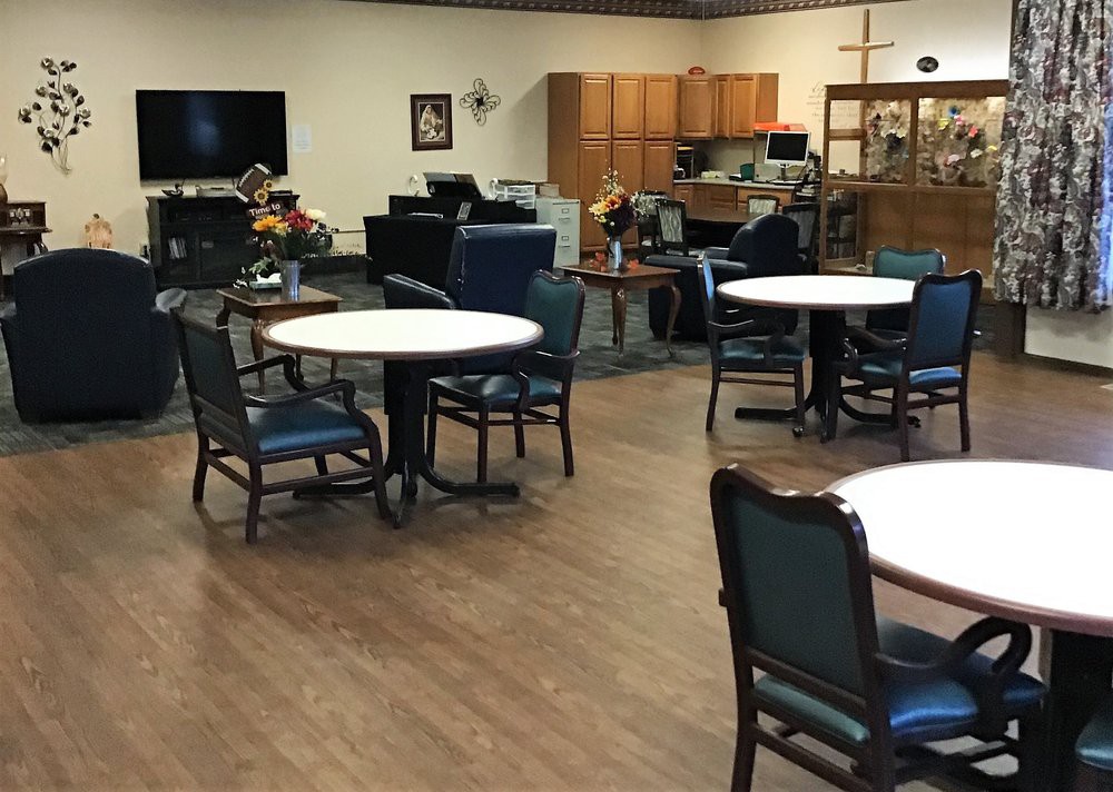 A community dining and recreation space with tables and chairs arranged in a cozy setting.
