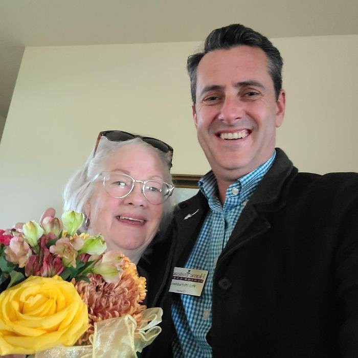 Two people smiling with a bouquet of flowers.