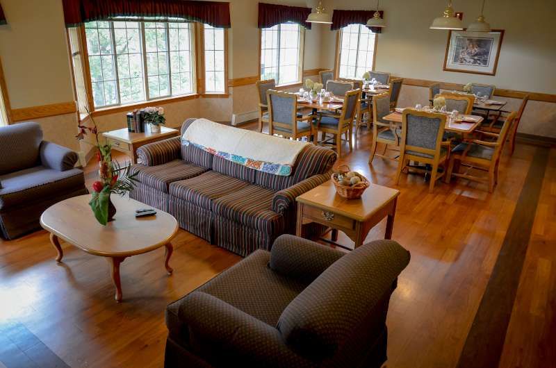 A cozy living room and dining area with sofas, chairs, and tables on a hardwood floor.