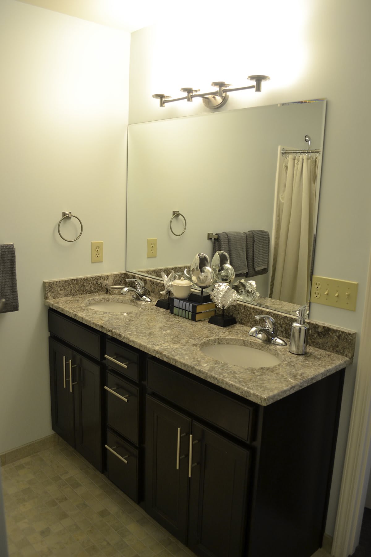 A neatly arranged bathroom with a large mirror, marble countertop, and stylish vanity.