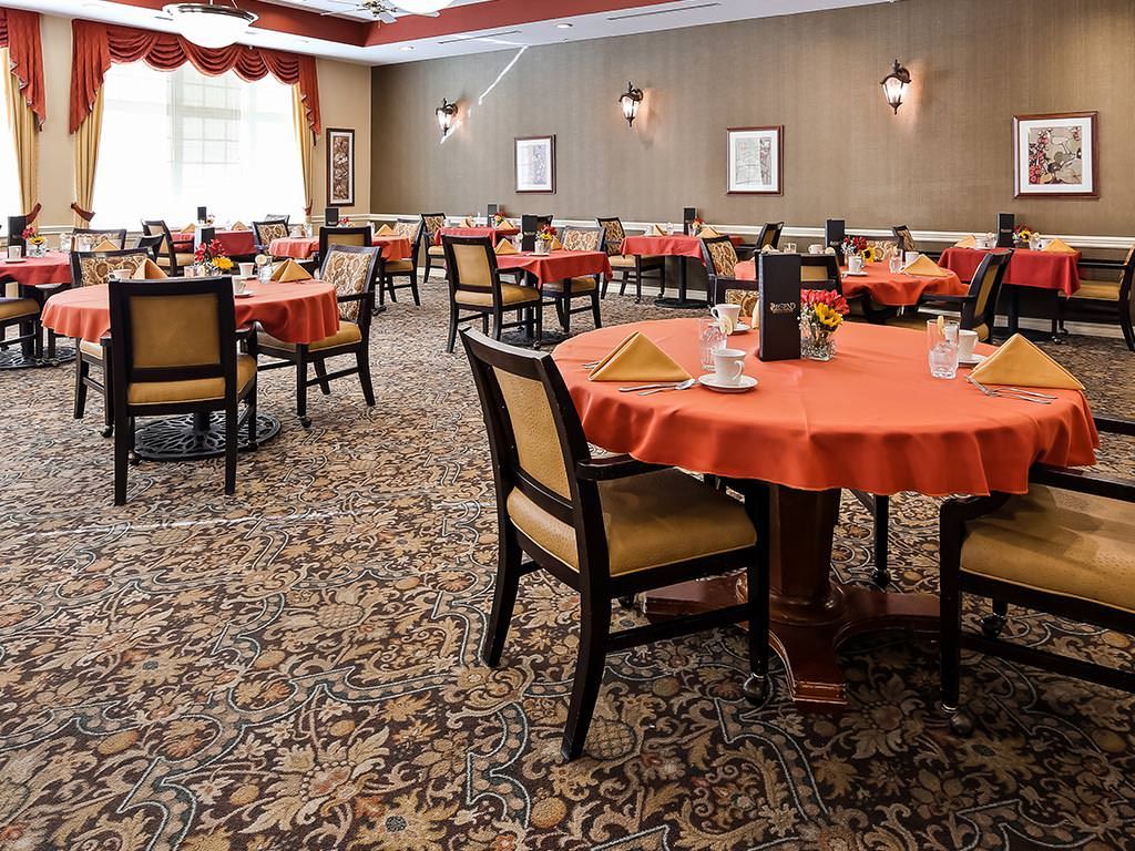 An elegant restaurant dining area with neatly arranged tables and chairs, featuring a patterned carpet and warm lighting.