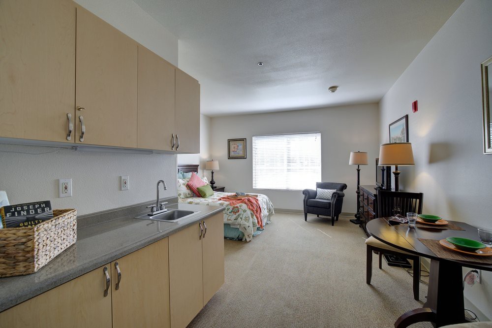 A cozy studio apartment with a kitchenette and a bed near the window.