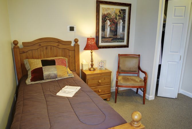 Cozy bedroom with a wooden bed, nightstand, and artwork on the wall.