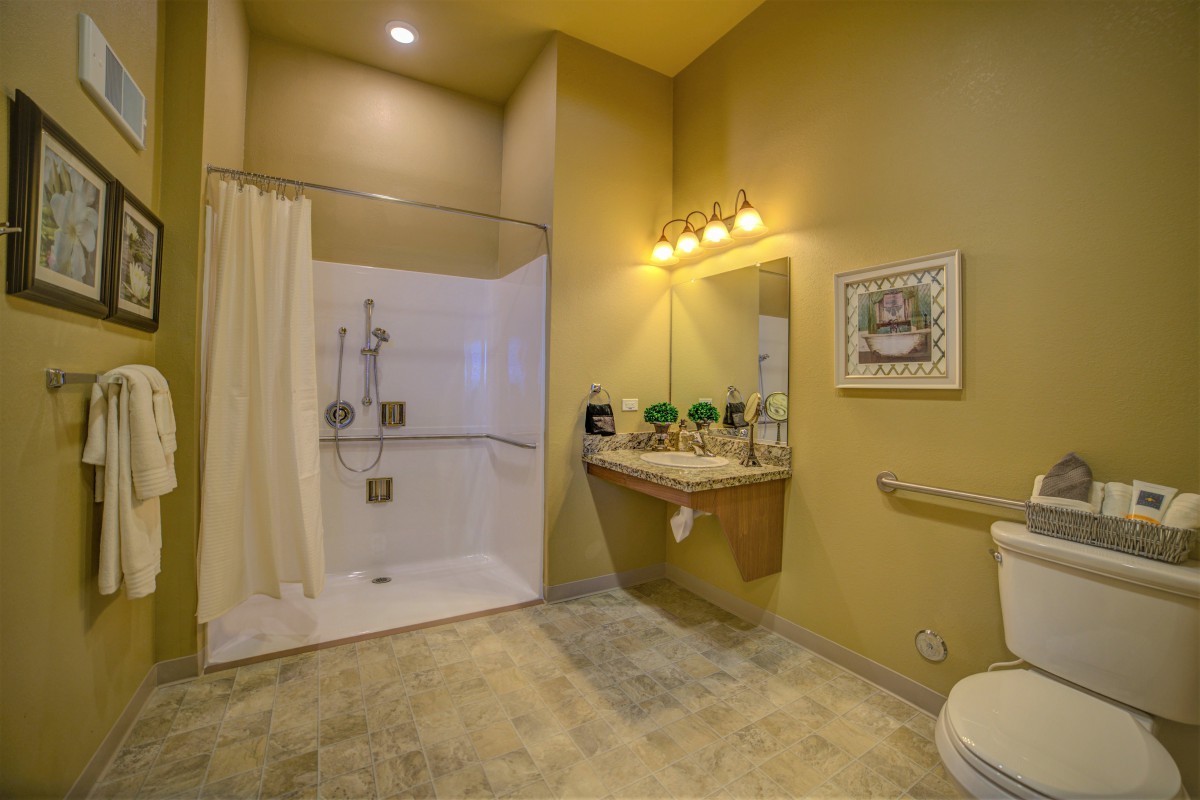 A modern bathroom with a spacious shower, large mirror, and elegant lighting.