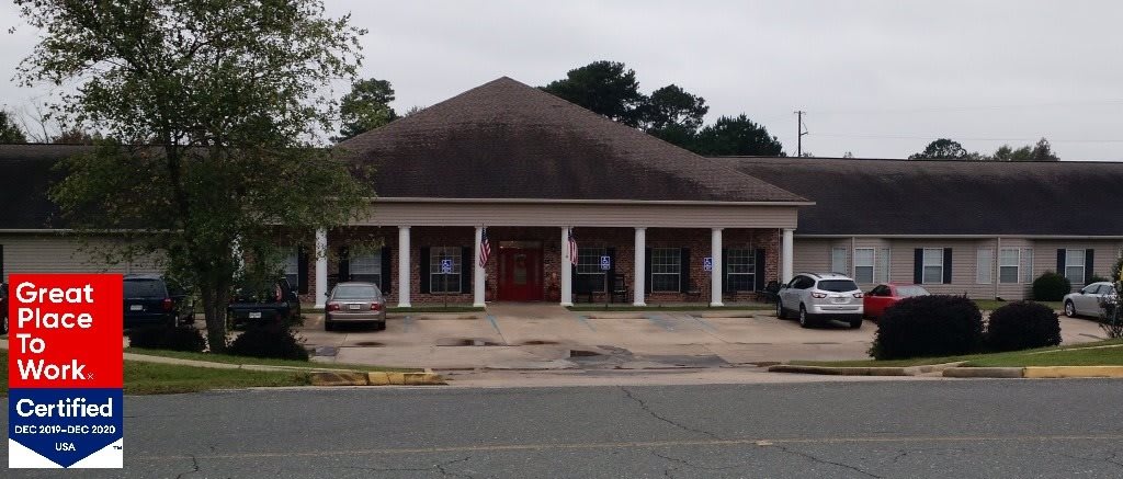 A small commercial building with a parking area in front, set against an overcast sky.