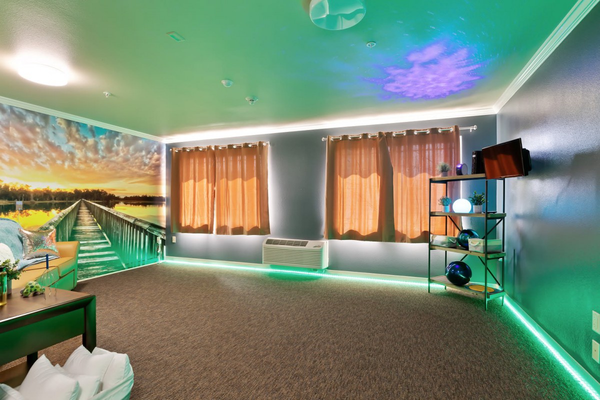 A modern room with ambient lighting, featuring curtains, shelves, and decorative elements.