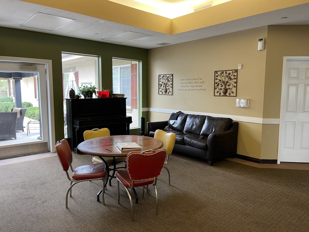 A cozy lounge area featuring a sofa, a round table with colorful chairs, and a piano.