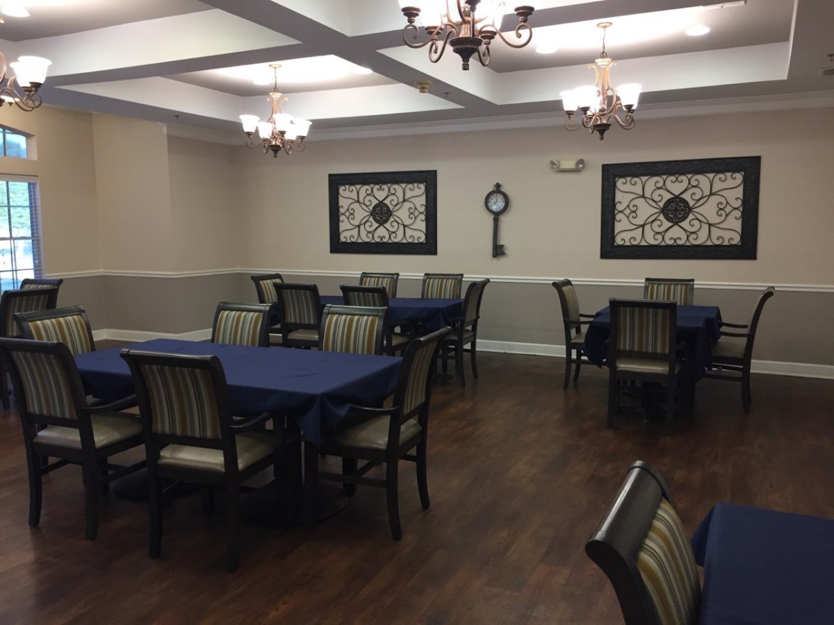 A well-decorated dining room with tables covered in blue tablecloths and elegant chandeliers hanging from the ceiling.