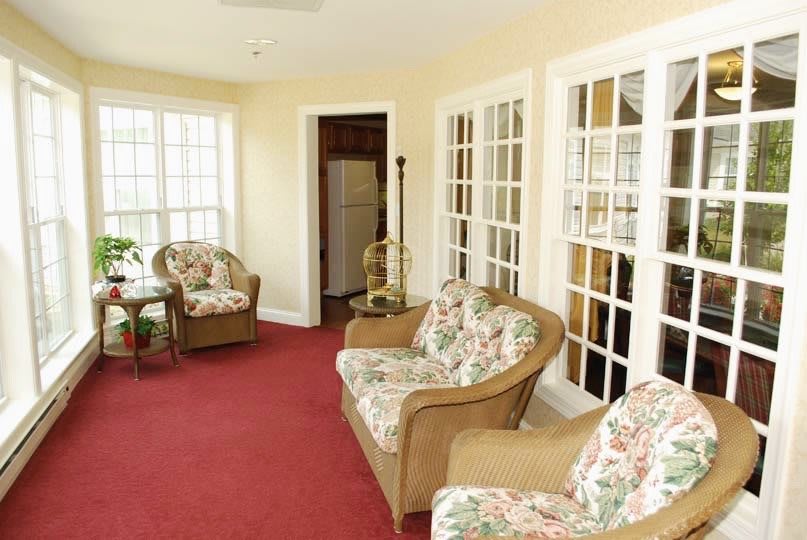 A cozy living room with floral armchairs and large windows.