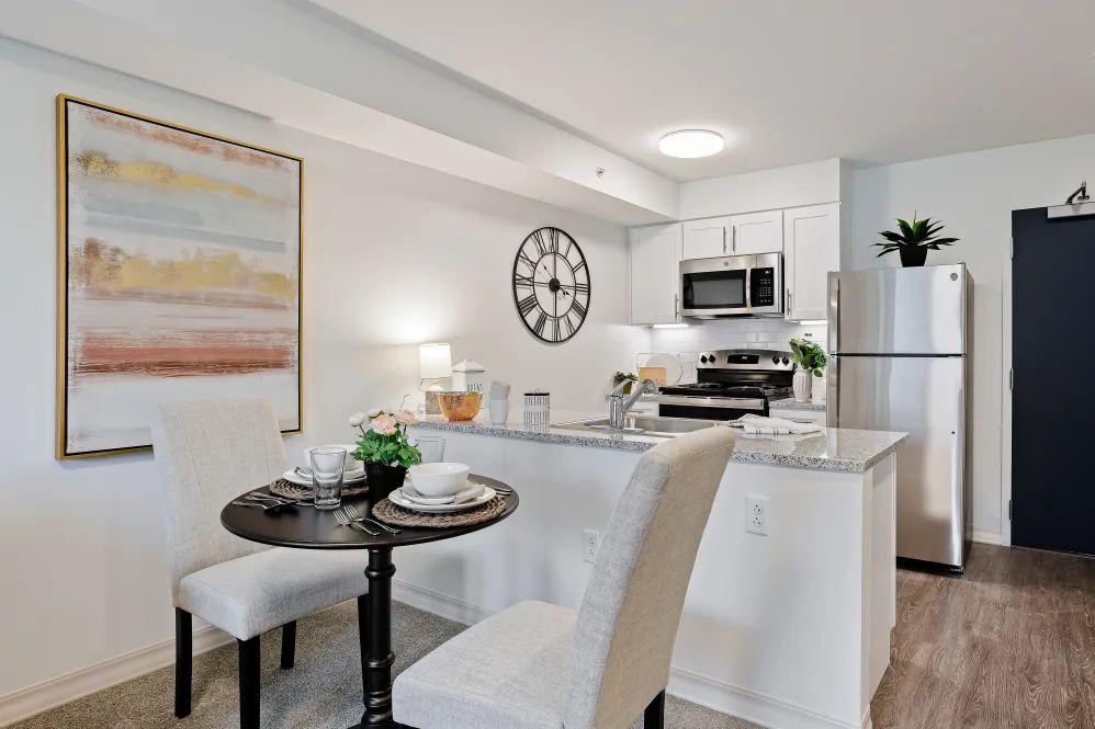 A modern kitchen with an open dining area featuring white decor and a minimalist design.