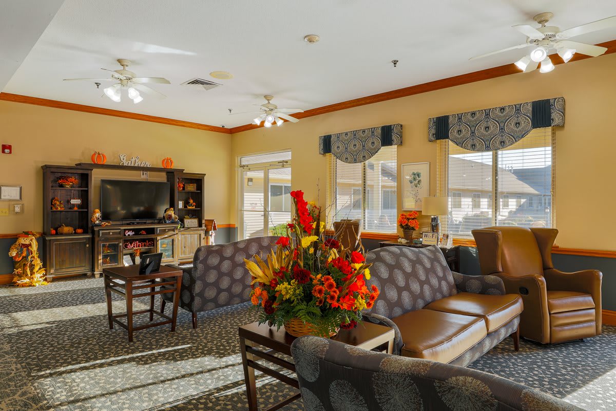 A cozy living room with comfortable seating, vibrant floral arrangement, and large windows allowing natural light.