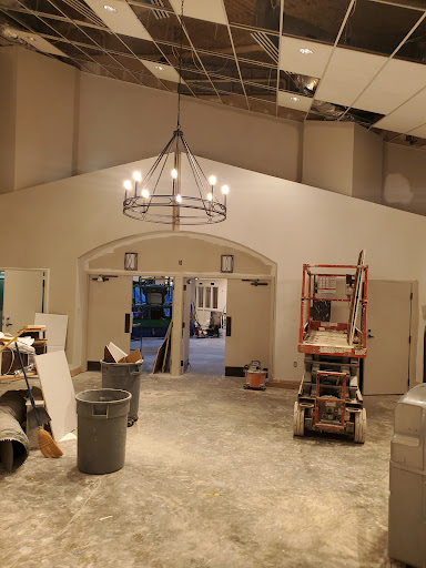 A view of an interior space undergoing renovation, featuring a chandelier and construction materials.