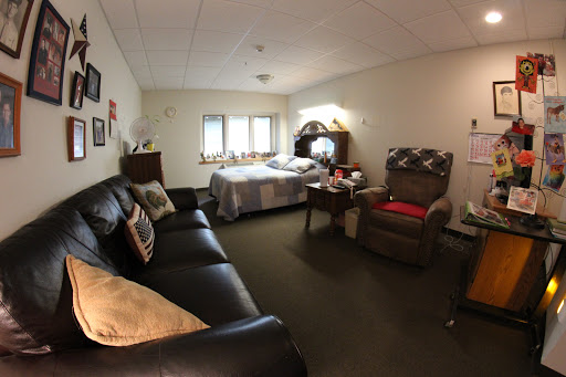 A cozy room featuring a bed, sofa, and armchair with soft lighting.