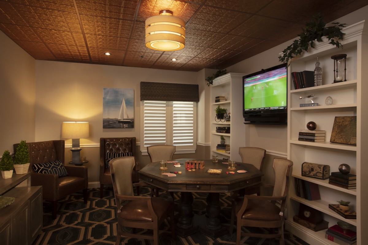 A cozy living room with a round table, chairs, and a television on the wall.