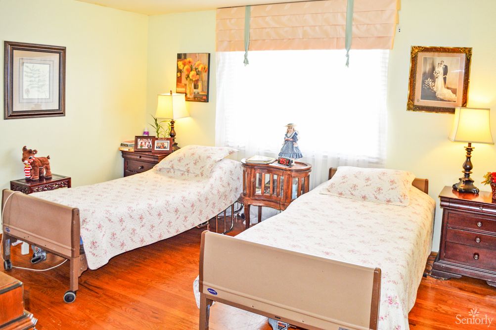 A cozy bedroom with two single beds, decorated with floral bedspreads and a lamp on a wooden nightstand.