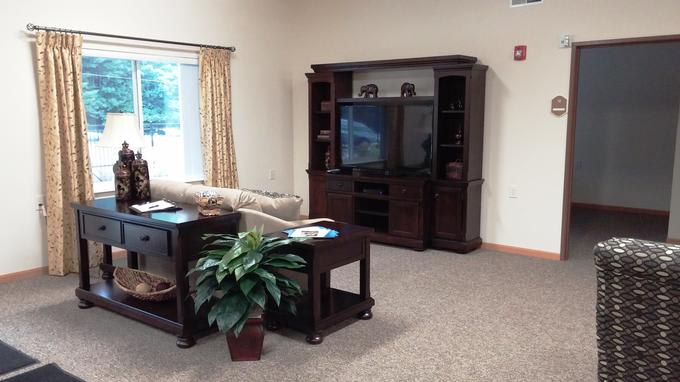 A cozy living room featuring a large entertainment center with a television, a comfortable couch, and a coffee table with a decorative plant.
