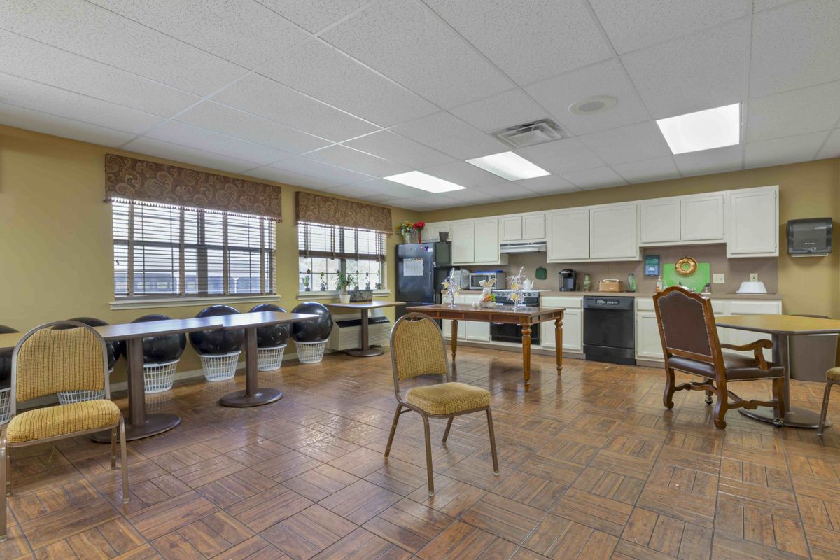 A spacious kitchenette with tables, chairs, and appliances.