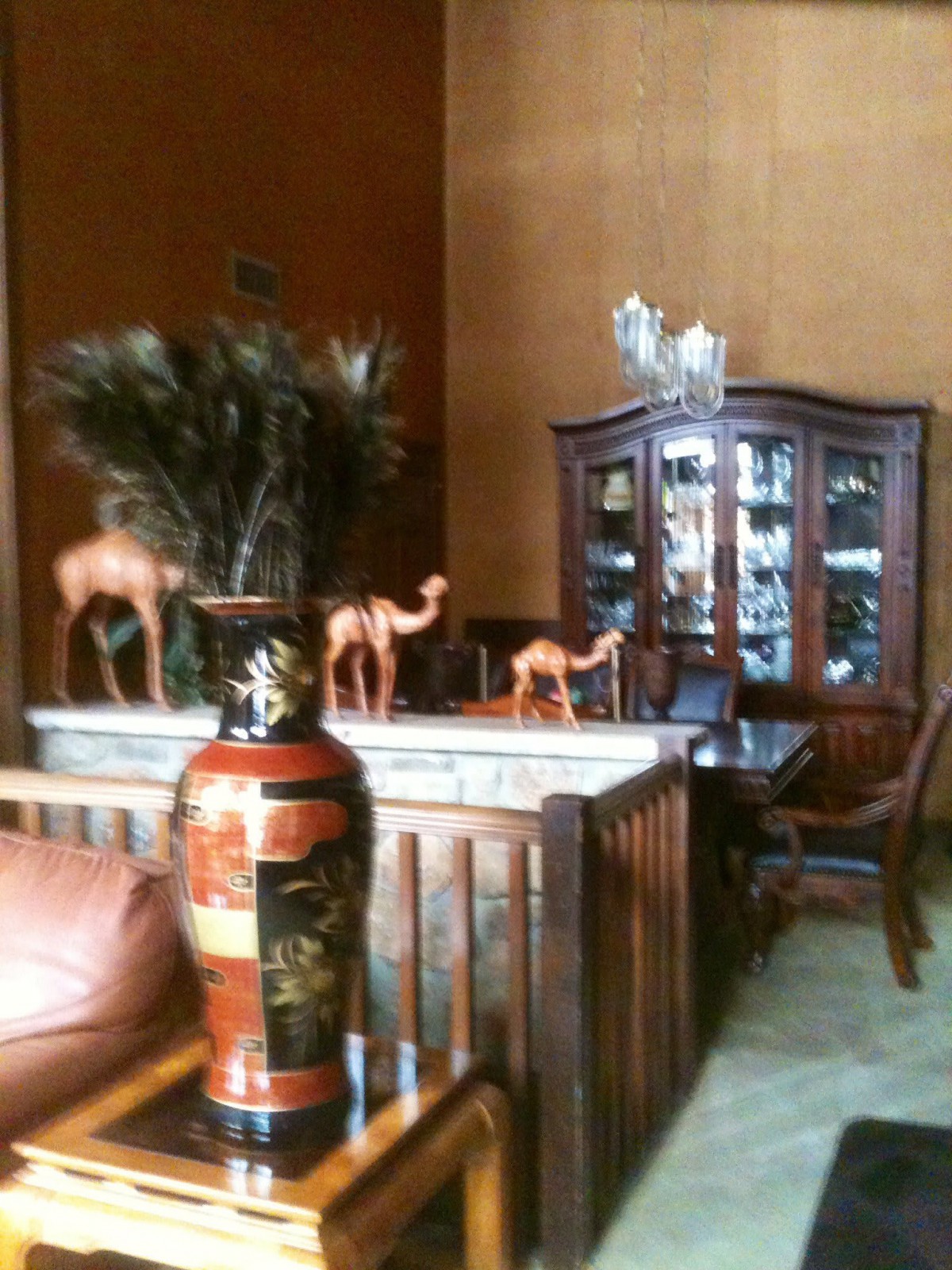 A cozy living room featuring decorative camels, a painted vase, and a wooden cabinet.