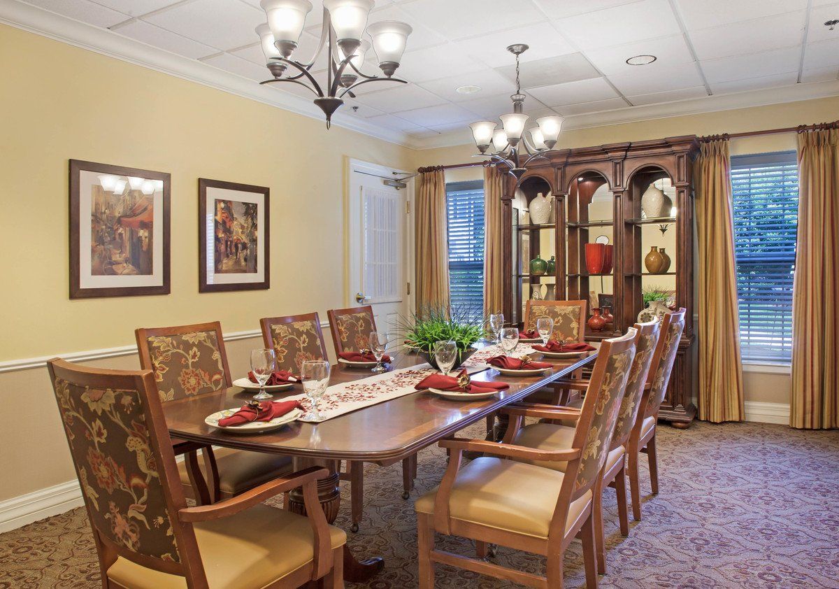 A beautifully decorated dining room with a chandelier, large wooden table, and matching chairs.