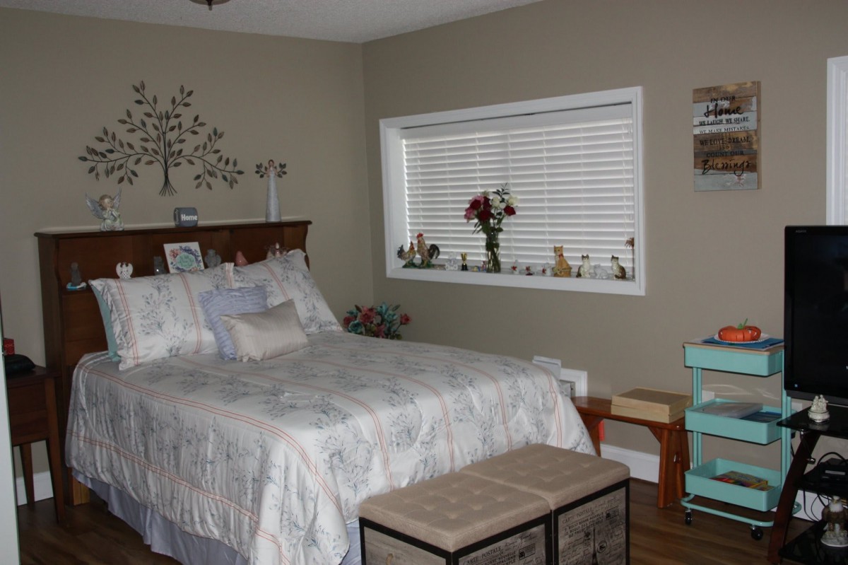 A cozy bedroom with a neatly made bed and decorative elements.