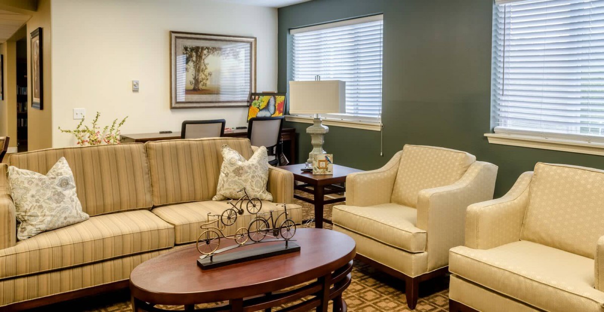 A cozy living room with a sofa, armchair, and coffee table, complemented by a lamp and wall decor.