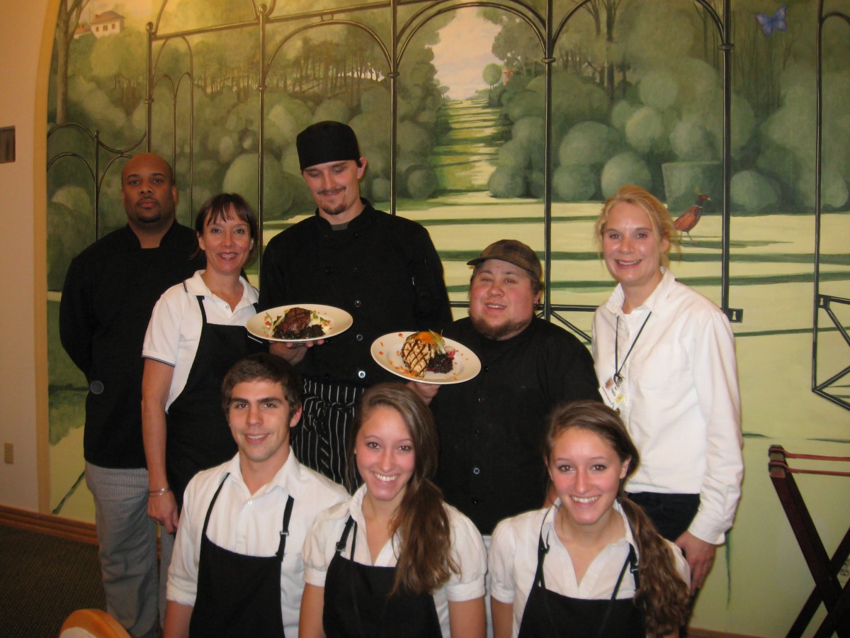 A team of restaurant staff posing together, showcasing dishes.