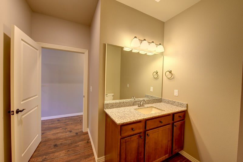 A bathroom featuring a wooden vanity with a large mirror and overhead lighting.