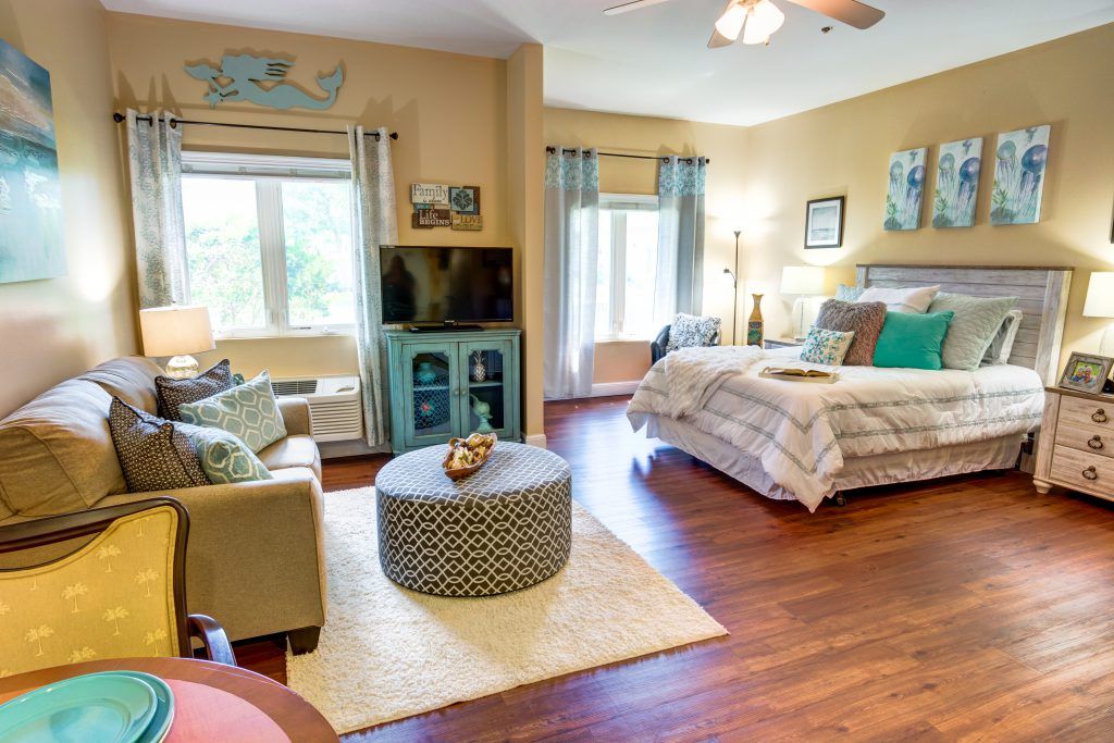 A cozy bedroom with a stylish interior design featuring wood flooring, comfortable seating, and decorative elements.