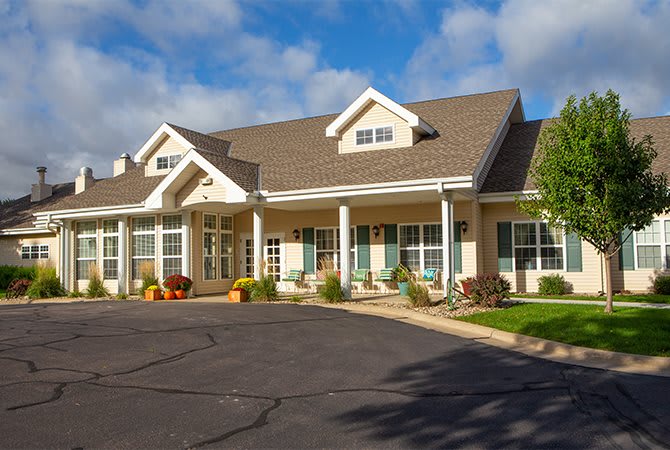 A suburban house with a spacious driveway under a blue sky.