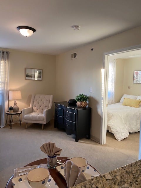 A cozy living room with a view into a softly lit bedroom, featuring elegant furniture and decor.